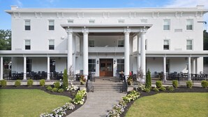 A white building with a central entrance, columns, and a covered porch with outdoor seating. - The White Inn (Fredonia)