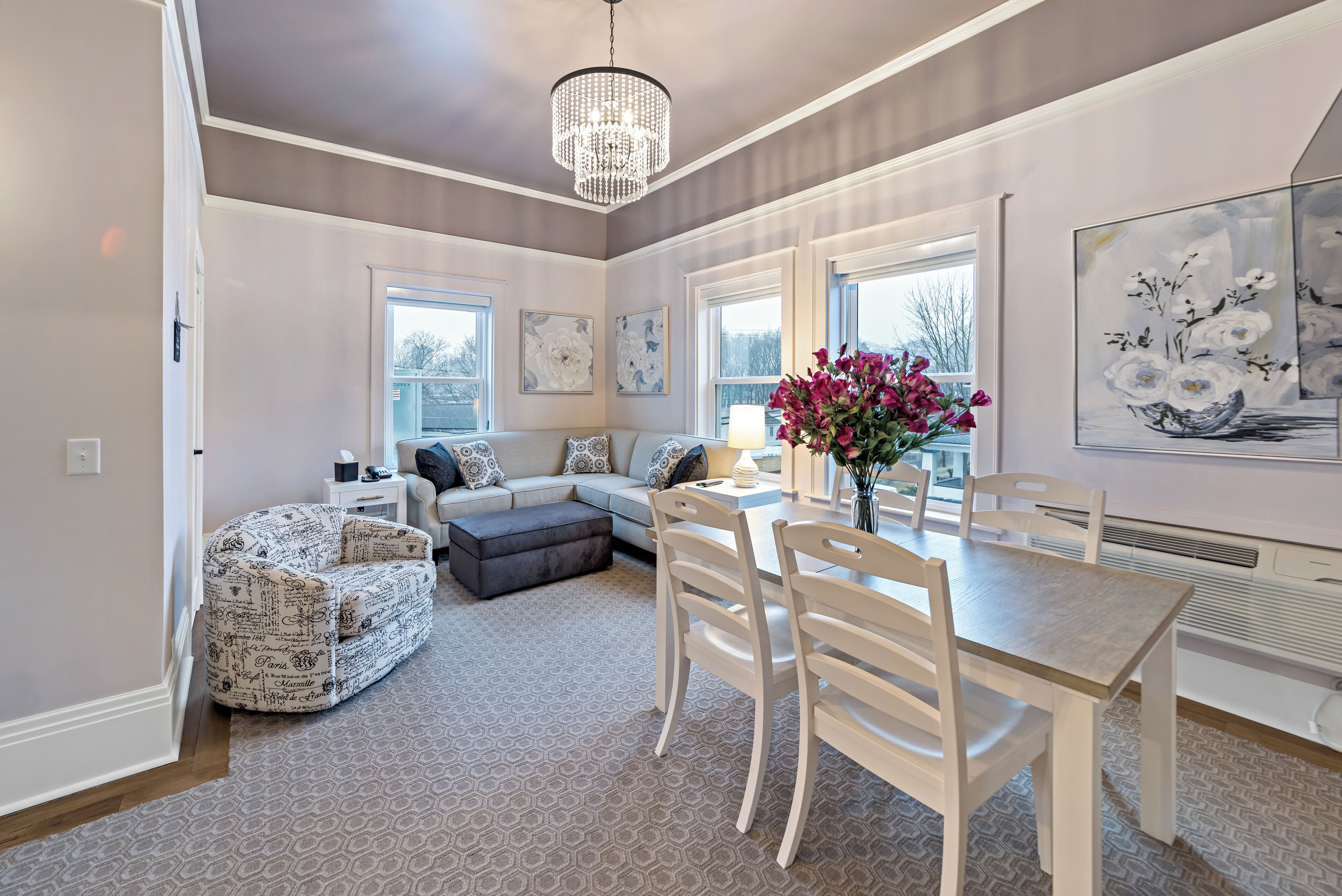 Ein geräumiges Wohnzimmer mit Essbereich, einer Chandelüster und Kunstwerken an den Wänden.