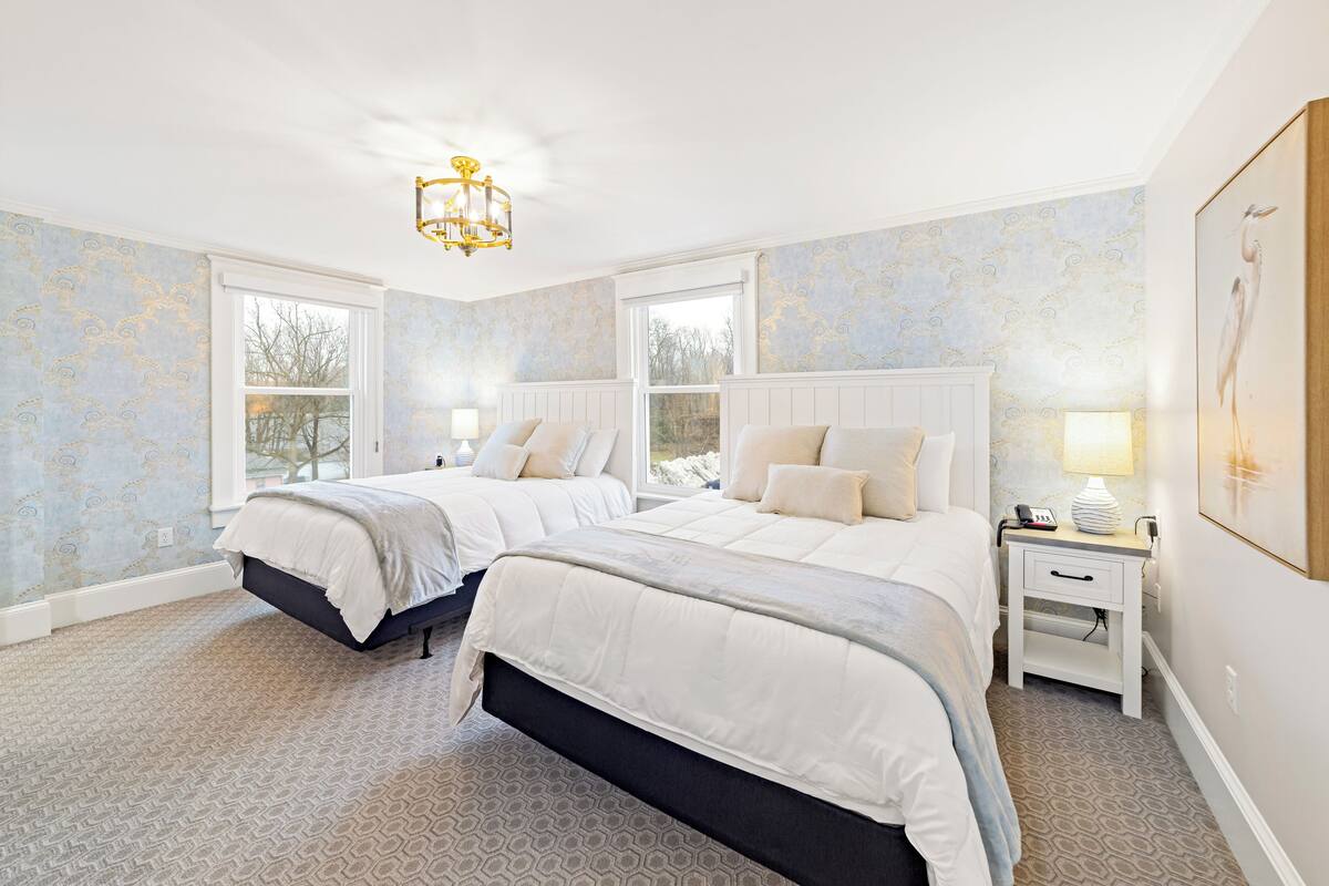 Ein Schlafzimmer mit zwei Betten, einem Nachttisch, einer Lampe und einem gerahmten Bild an der Wand.