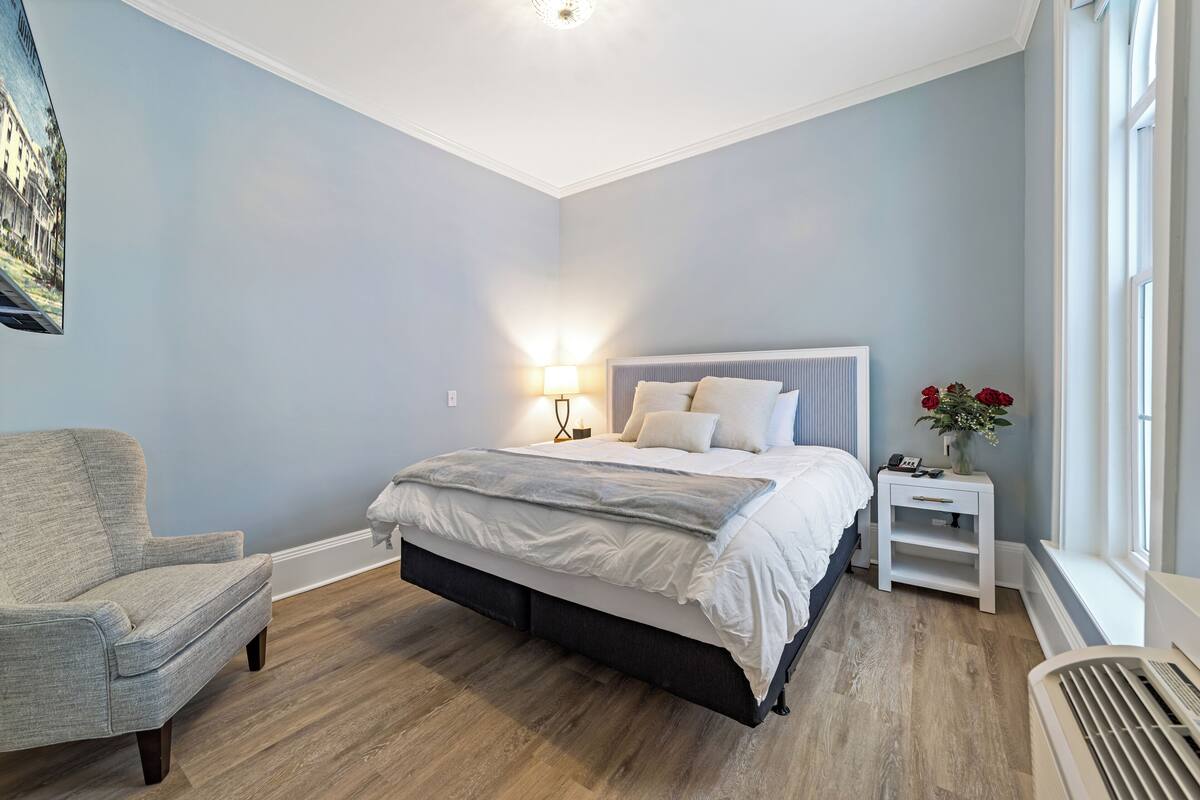 Ein Schlafzimmer mit Bett, Stuhl, Nachttisch und Fenster.