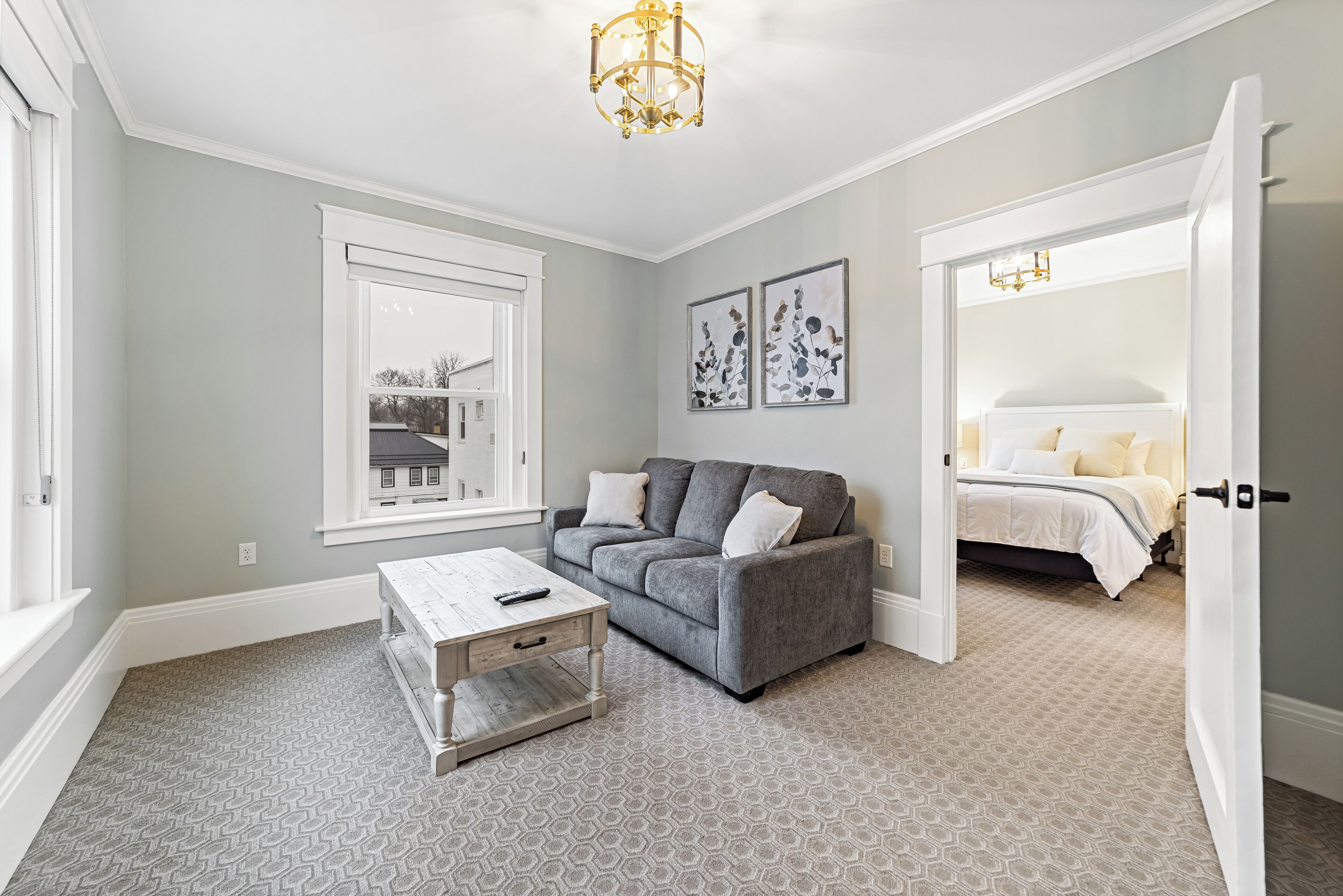 A modern living room with a grey sofa, a wooden coffee table, and a patterned carpet.