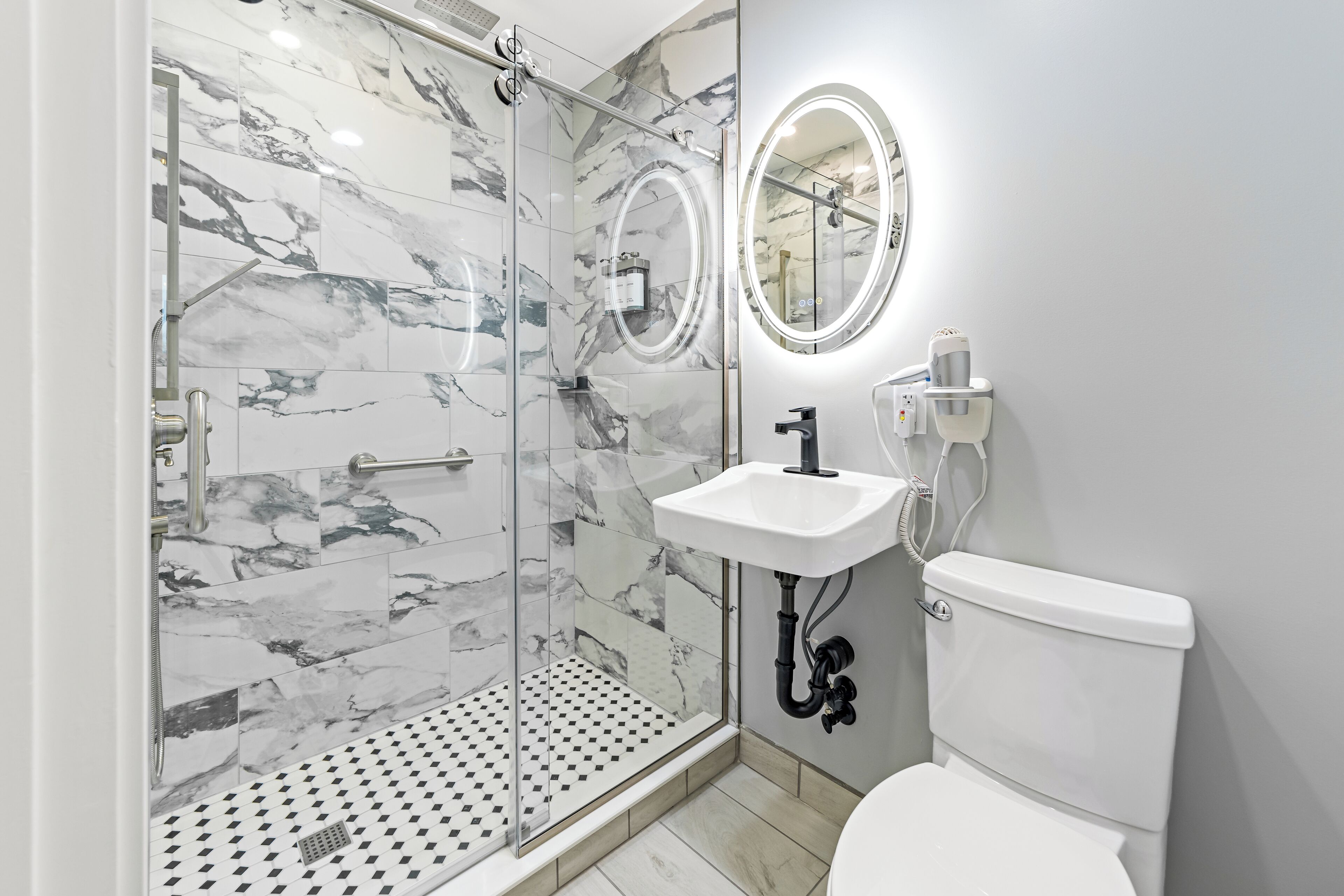 A modern bathroom with a glass-enclosed shower, a white sink, and a toilet.