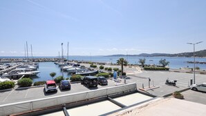 A marina with boats docked, a parking area, and a view of the sea and distant hills. - Nice apartment in Sainte-Maxime with WiFi (Sainte-Maxime)
