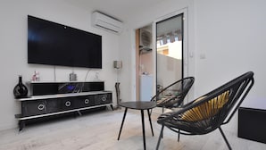 A modern living room with a flat-screen TV, a black marble console, two black wicker chairs, and a small round table. - Nice apartment in Sainte-Maxime with WiFi (Sainte-Maxime)