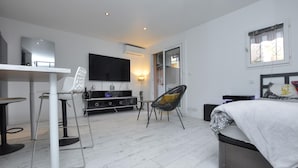 A modern bedroom with a bed, a TV, a desk with a chair, and a sofa. - Nice apartment in Sainte-Maxime with WiFi (Sainte-Maxime)