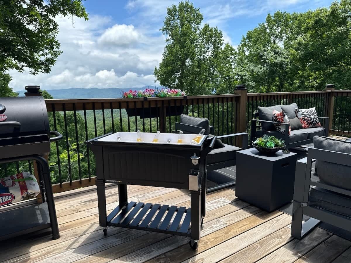 Una terraza exterior con una parrilla, un carrito de bar y una zona de estar con un sofá y sillas.