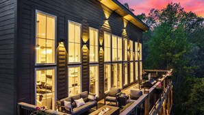 Ein modernes Haus mit einer großen Terrasse, zahlreichen Fenstern und Sitzgelegenheiten im Freien.