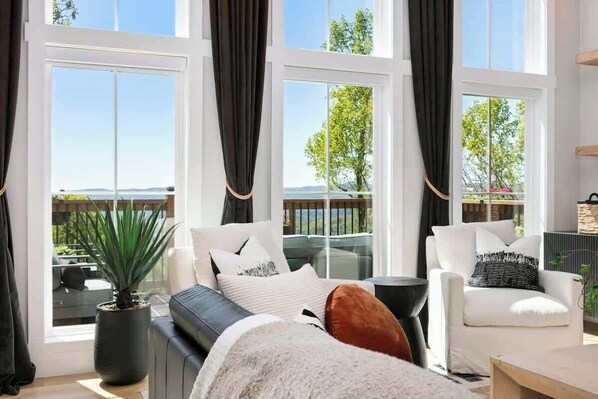 A modern living room with large windows, a sofa, a chair, and a coffee table.