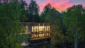 Eine zweistöckige Holzhütte mit Balkon, umgeben von dichtem Wald.