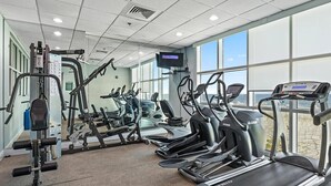 Un gimnasio con cintas de correr, elípticas y equipo de pesas.
