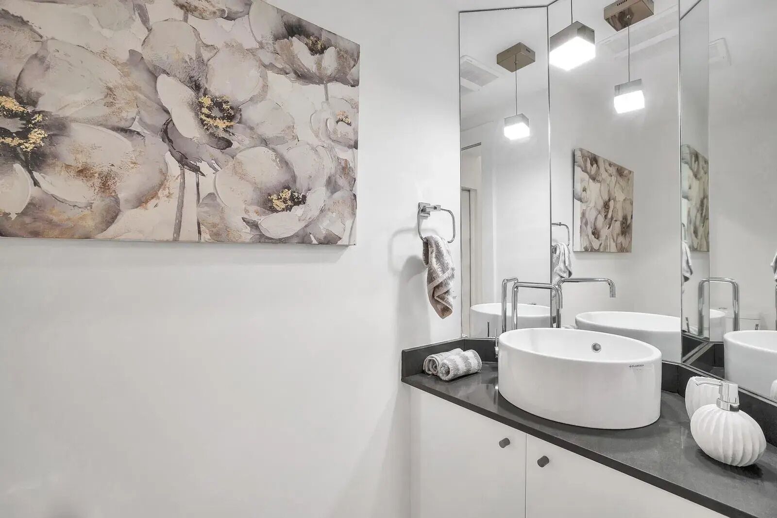 Een moderne badkamer met twee wastafels, een grote spiegel en abstracte wanddecoratie.