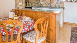 A cozy kitchen with wooden cabinets, a tiled backsplash, and a dining area with a table set for two. - The Old Shippen - UK48328 (Lifton)