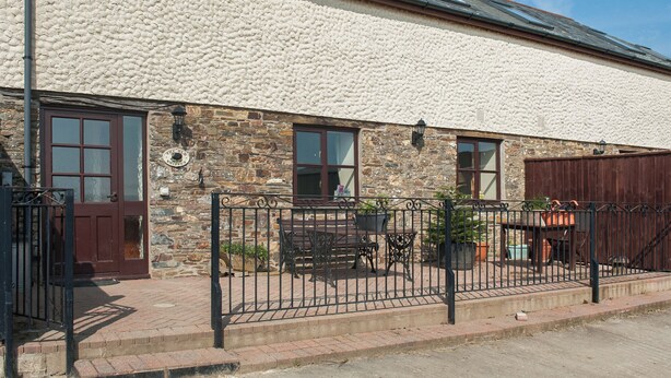 A two-story building with a stone facade, a wooden door, and a metal gate. - The Old Shippen - UK48328 (Lifton)