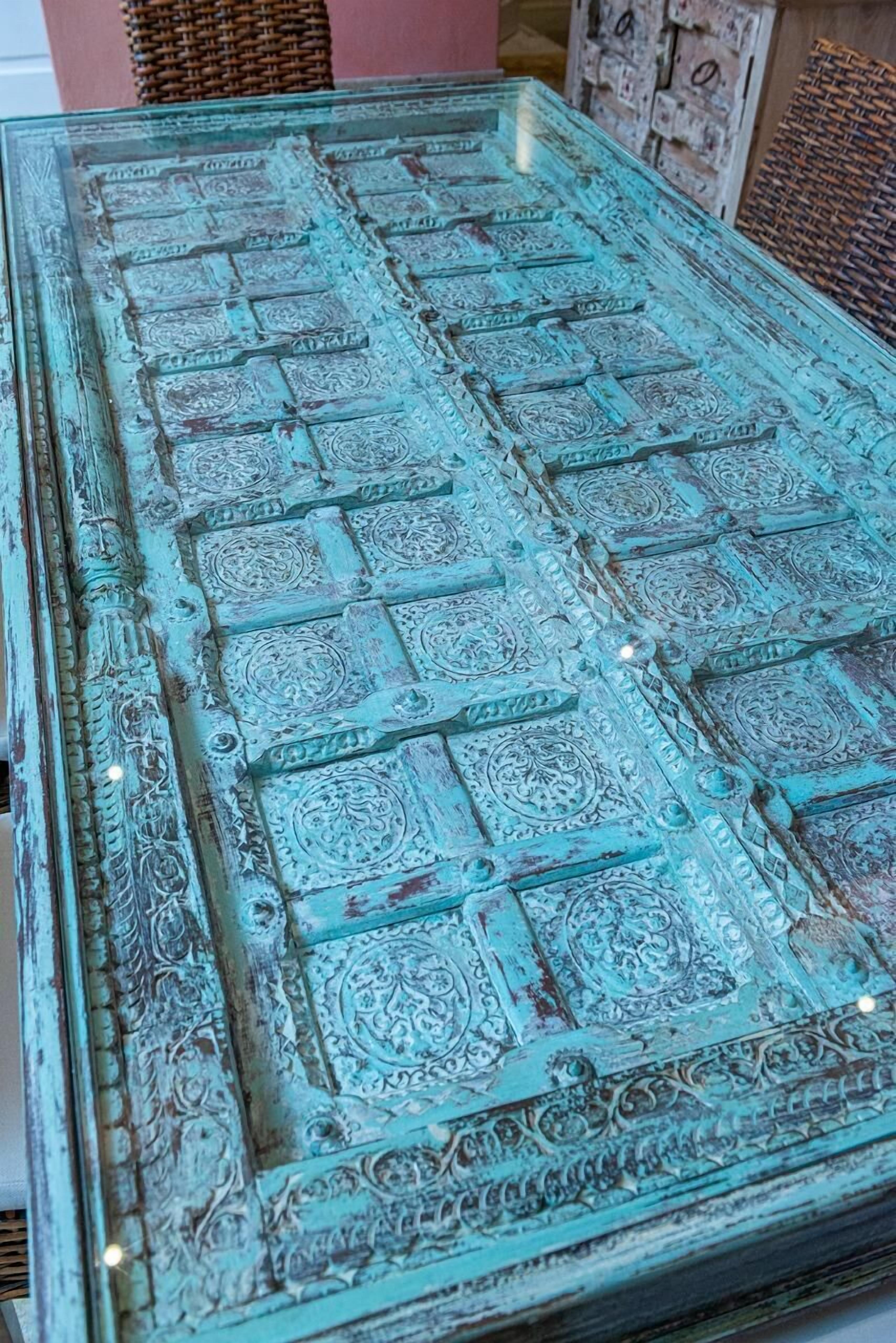 Une table en verre ornée de motifs complexes en relief et dotée d’un aspect rustique et vieilli.
