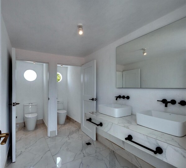 A modern bathroom with two sinks, a large mirror, and a toilet visible through an open door. - Upper House (Cartagena)