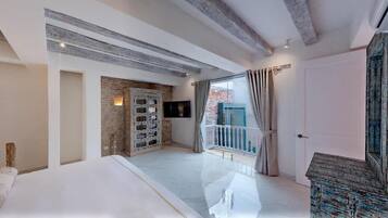 Un dormitorio moderno con una cama grande, televisión y balcón con cortinas.
