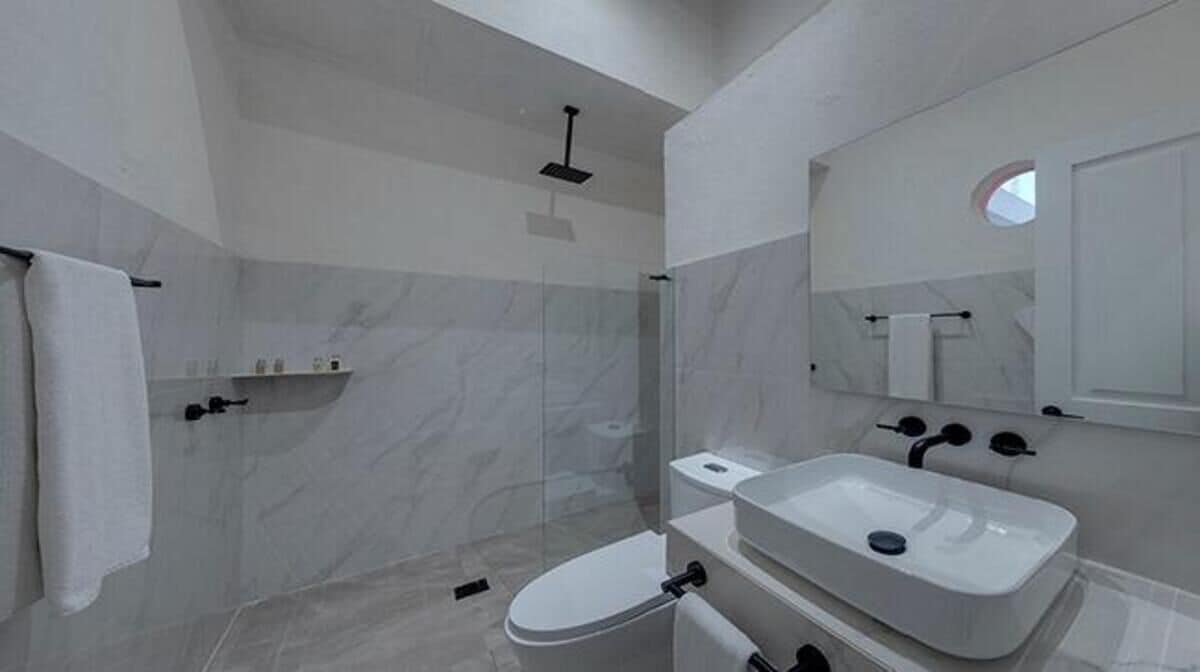 A modern bathroom with a glass-enclosed shower, a white toilet, and a sink.