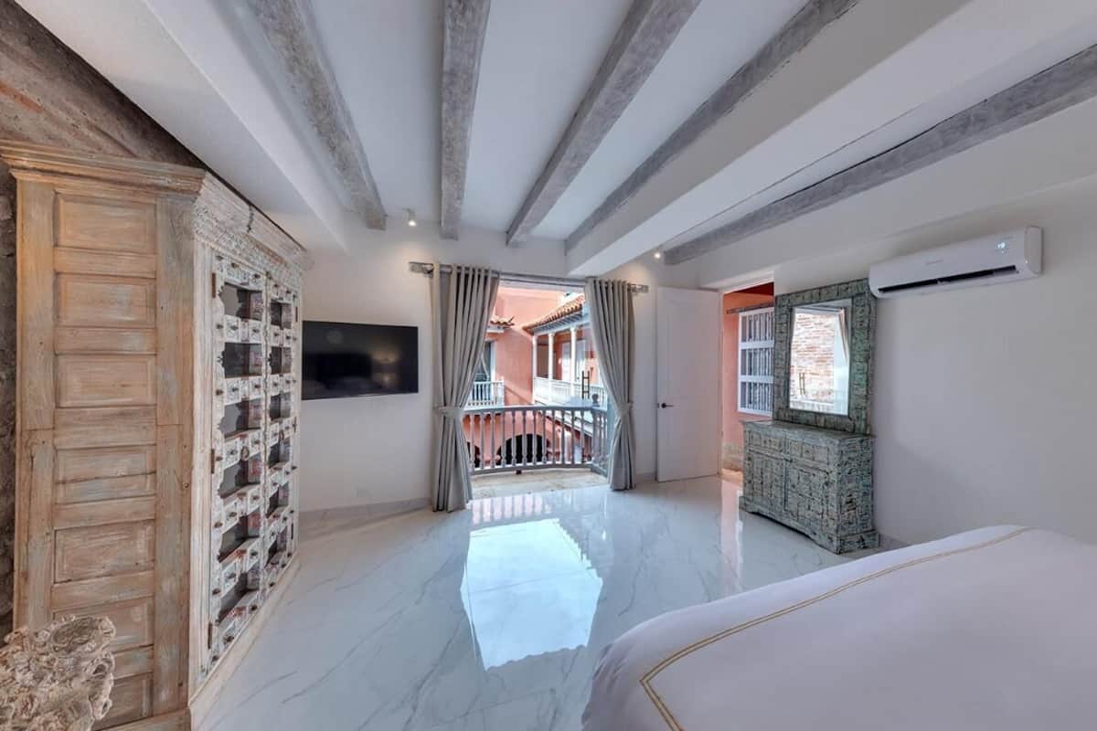 Um quarto espaçoso com uma cama grande, um armário de madeira, uma TV e uma varanda com vista.
