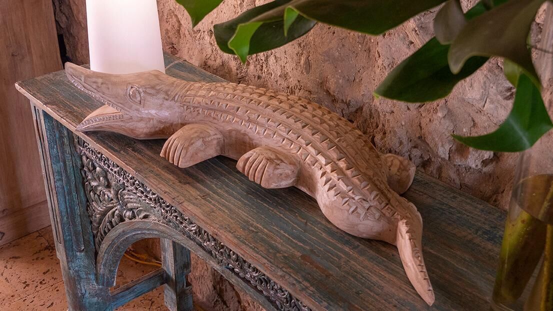 Eine Holzskulptur eines Krokodils auf einem rustikalen Holztisch.