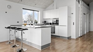 A modern kitchen with a large island, bar stools, and a view of the outdoors.