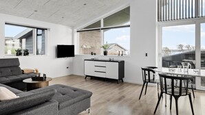 A modern living space with a sofa, dining table, and TV.