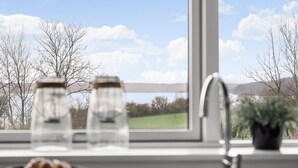A kitchen with a window view of a landscape, a sink, and a potted plant.