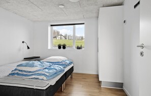 Relax in a serene bedroom with a neatly made bed, bedside table, and window offering a view of the surrounding landscape.