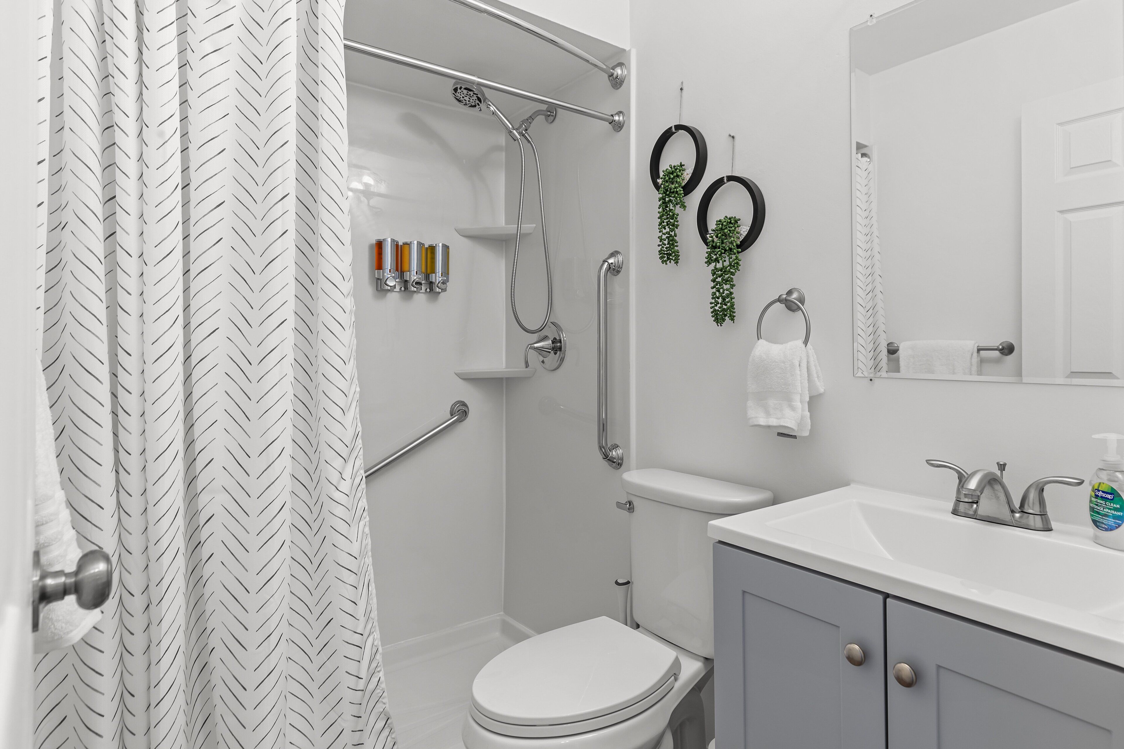 A modern bathroom with a shower, toilet, sink, and a mirror.