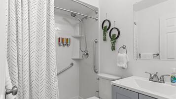 A modern bathroom with a shower, toilet, sink, and a mirror.