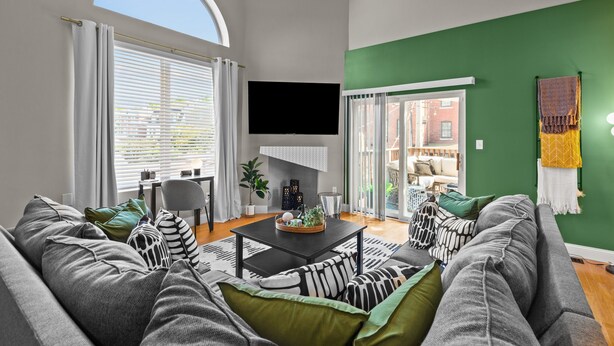 Una sala moderna con un sofá gris, una mesa de centro negra y una pared de acento verde.