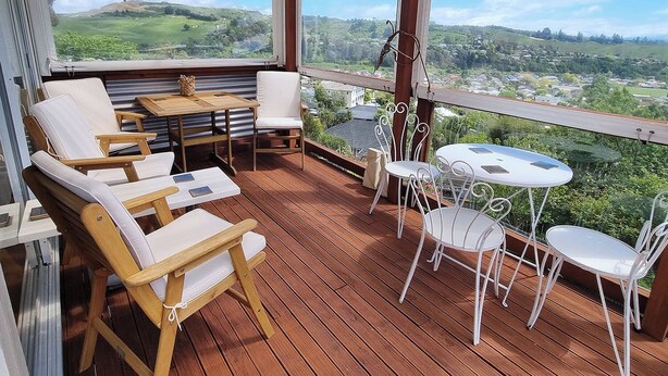Um deck de madeira com móveis de exterior, incluindo cadeiras e mesas, com vista para uma paisagem deslumbrante.