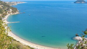 A coastal view with a clear beach, calm sea, and a distant island. - Nice home in Lusignano d'Albenga (Lusignano d'Albenga)