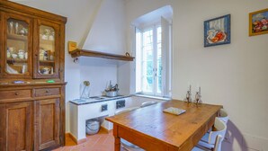 A kitchen with a wooden table, white chairs, a stove, and a window. - Nice home in Lusignano d'Albenga (Lusignano d'Albenga)