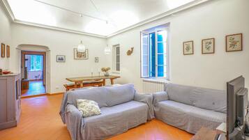 Un salon avec un canapé, un téléviseur et une table à manger.