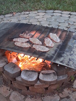 Un gril placé au-dessus d’un foyer où la viande est en train de cuire.