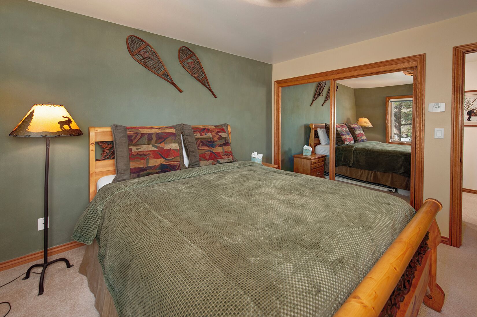 Een slaapkamer met een groot bed, een nachtkastje, een spiegel en een lamp.