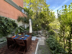 An outdoor dining area with a brick patio, wooden table, and chairs. - Isa's Garden (Monterosso al Mare)