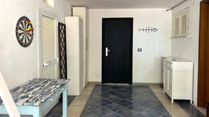 A hallway with a black door, a dartboard, and a patterned table. - Isa's Garden (Monterosso al Mare)