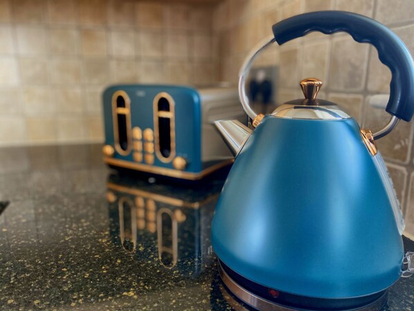 Un bollitore blu su un piano di lavoro della cucina, con un tostapane sullo sfondo.