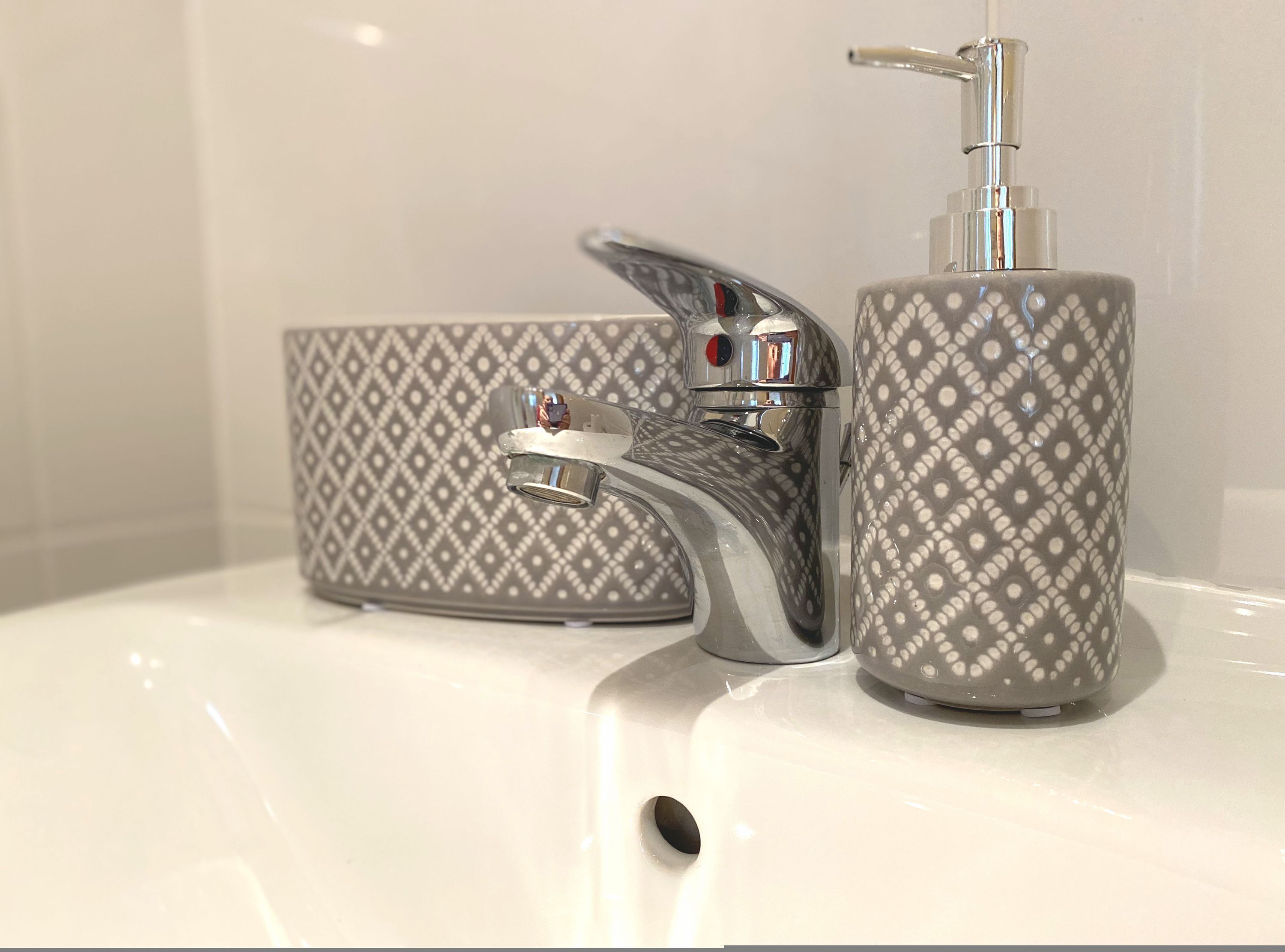 Un lavamanos de baño con un grifo moderno y un dispensador de jabón.