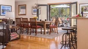 Un comedor amplio con sillas de madera y una mesa, una sala de estar acogedora con un sofá y una mesita de centro, y un ventanal que ofrece vistas al exterior.