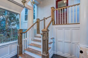 A staircase with wooden balusters and a handrail, leading to a landing with a red door. - Relaxing King Bed Suite Close to Lunenburg Harbour (Suite 2) (Lunenburg)