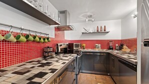 A modern kitchen with a checkered floor, red and white tiles on the backsplash, stainless steel appliances, and a variety of utensils and cookware. - RMR: Tensleep B4 Condo in Teton Village (Teton Village)