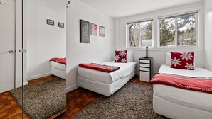 A bedroom with two beds, a window with a view of trees, and a door with a mirror. - RMR: Tensleep B4 Condo in Teton Village (Teton Village)