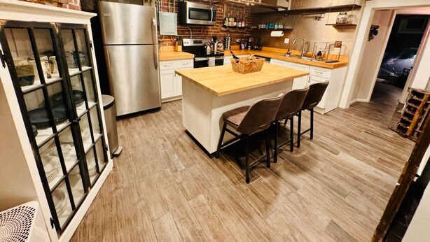 Et moderne køkken med en central ø, rustfrie stålgadgetter og en backsplash i mursten.