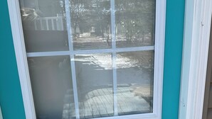 A turquoise door with a window and a doorbell.