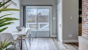 Une cuisine moderne avec des meubles blancs, un évier en acier inoxydable et une grande fenêtre donnant sur une terrasse.