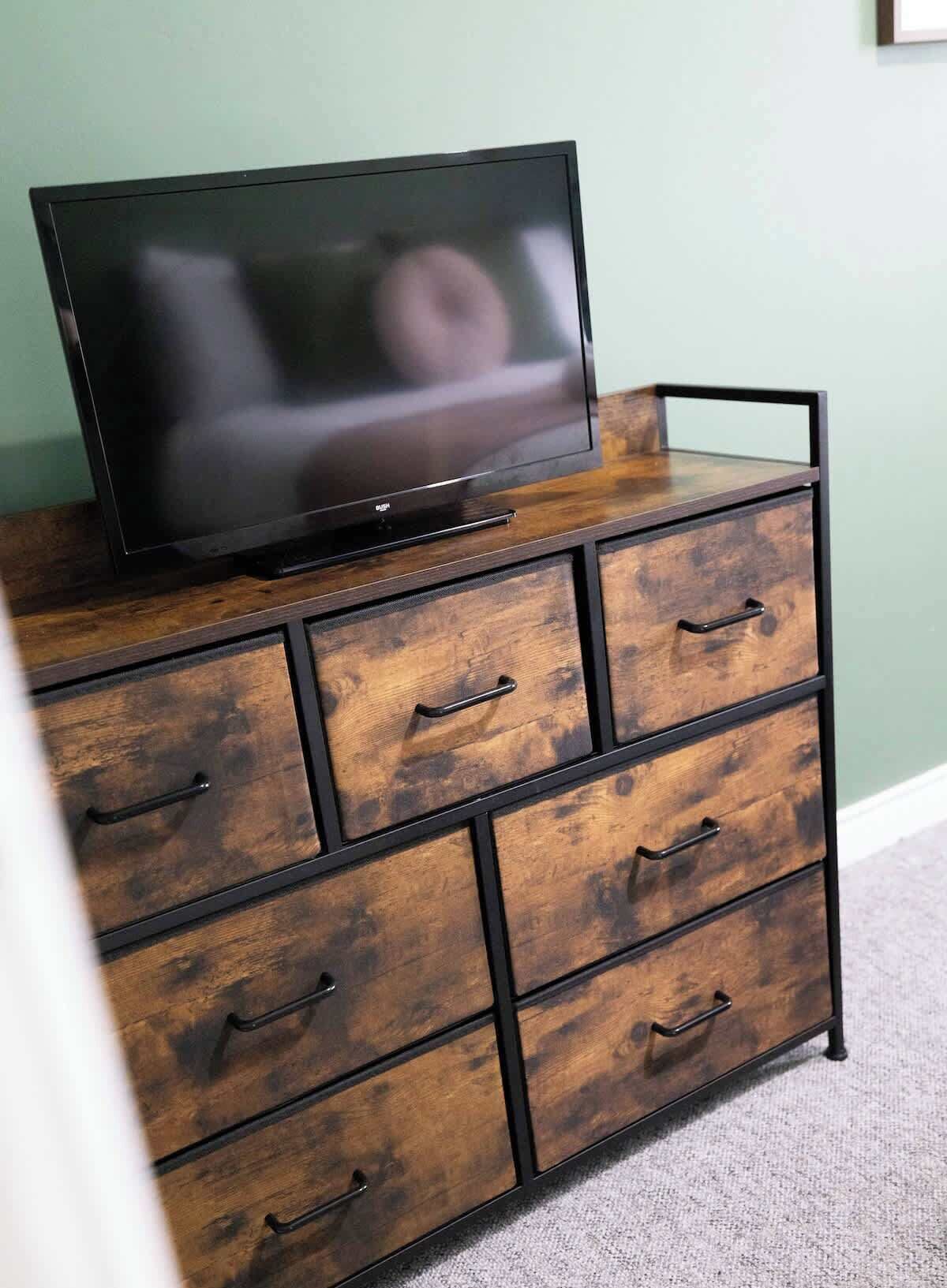 Un aparador de madera con cajones y un televisor encima.