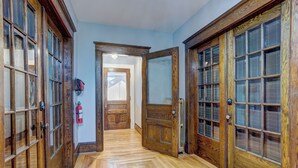 A hallway with wooden doors and a fire extinguisher on the wall.