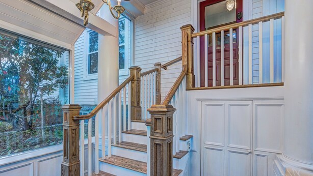 A staircase with wooden balusters and a handrail, leading to a landing with a red door.